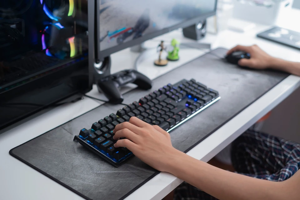 Bureau gaming moderne avec utilisateur tapant sur clavier mécanique rétroéclairé
