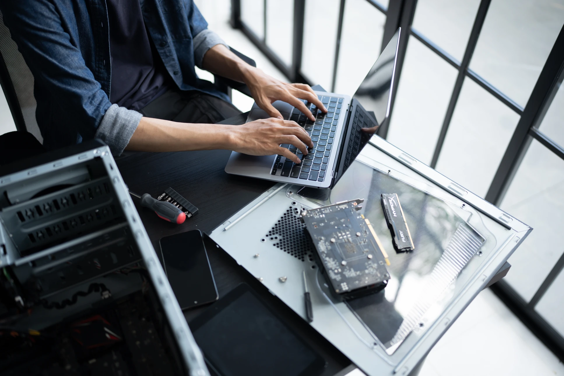 Technicien informatique professionnel effectuant une intervention de maintenance sur une tour d'ordinateur de bureau, en train de vérifier les composants internes ou de remplacer des pièces, dans un environnement de bureau ou atelier technique moderne. L'image doit montrer clairement l'action de maintenance/dépannage informatique en cours, avec le matériel informatique en focus.