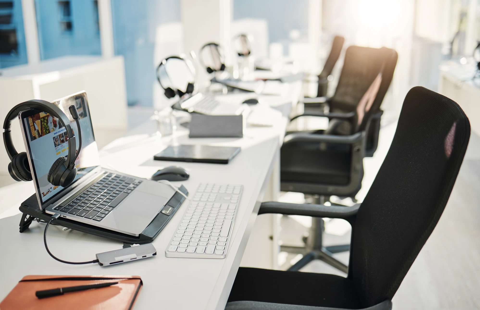 Femme professionnelle travaillant dans un bureau moderne, assise devant un ordinateur portable et écran externe, vêtue d'une chemise rouge